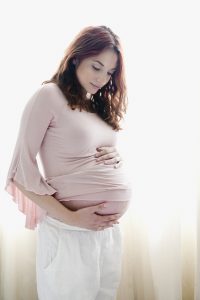 Pregnant Hispanic woman holding stomach