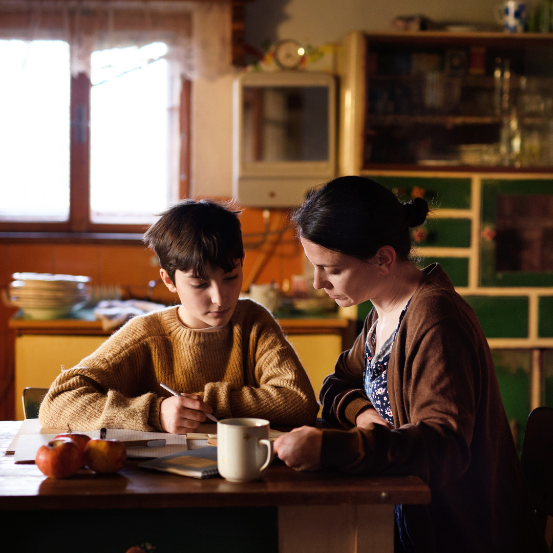 Poor mature mother and small daughter learning indoors at home, poverty concept